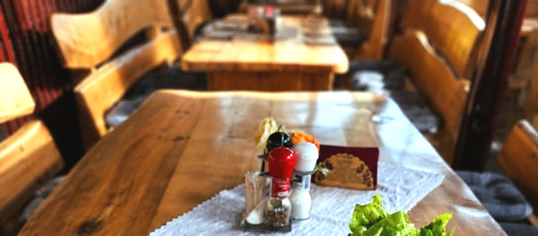 A Holiday Cafe belső tere: fapadok és tömör fa asztalok, terítővel megterítve