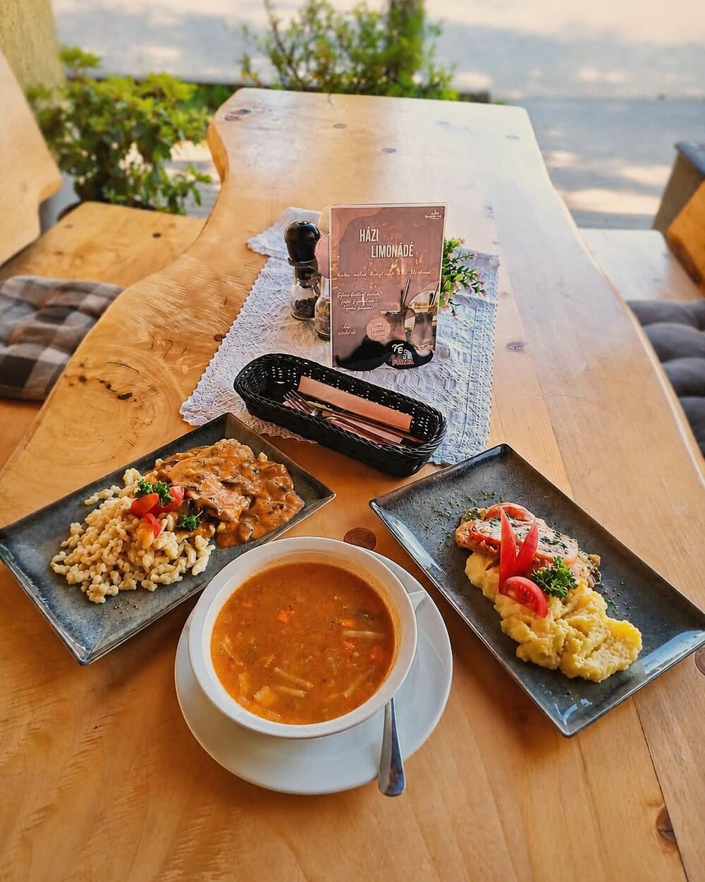 Megterített asztal a Holiday Cafe teraszán, leves és két főétel a fatáblán